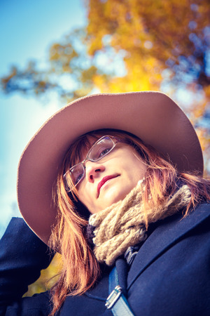 Beautiful woman in a hat walking in the autumn park. Bottom view.の写真素材