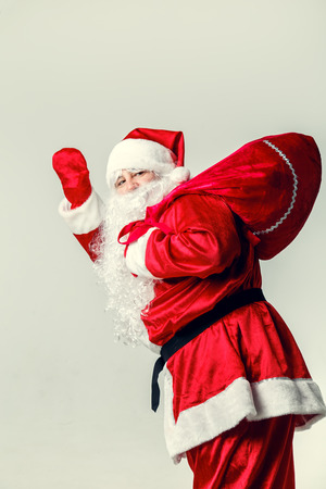 Santa Claus going with a bag of gifts on a white background.の写真素材