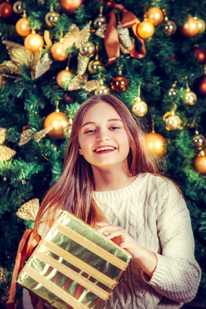 Beautiful laughing girl with gift box near Christmas tree.の写真素材