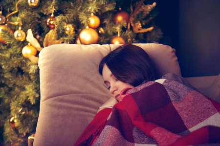 Beautiful girl sleeping near a Christmas tree.の写真素材