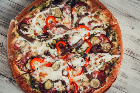 Delicious pizza with salami, cheese, peppers and meat, cut into slices.の写真素材