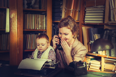 Mother and son sitting at an old typewriter in the library.の写真素材