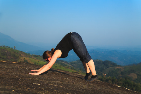 Woman practicing yoga outdoors. Beautiful mountain landscape. The concept of a healthy lifestyle.の写真素材