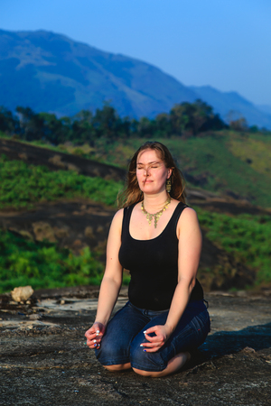 Woman practicing yoga outdoors. Beautiful mountain landscape. The concept of a healthy lifestyle.の写真素材
