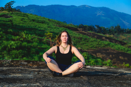 Woman practicing yoga outdoors. Beautiful mountain landscape. The concept of a healthy lifestyle.の写真素材