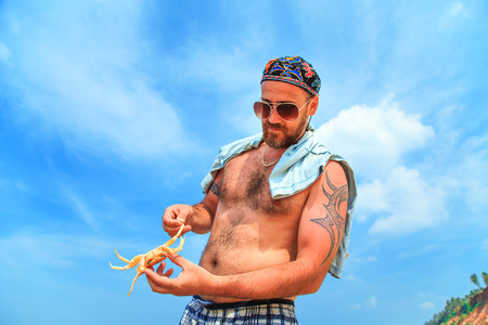 Man catches a crab on the sandy beach of the Indian Ocean.の写真素材