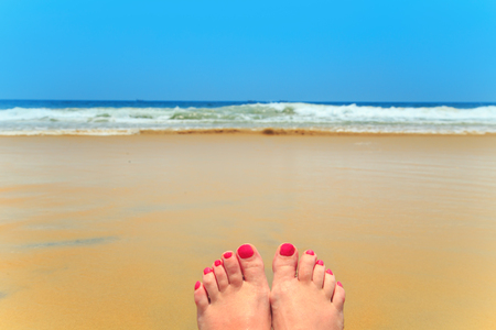 Female legs on the beach. The concept of summer vacation.の写真素材
