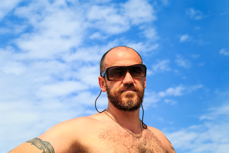 Portrait courageous bearded man against a blue sky.の写真素材