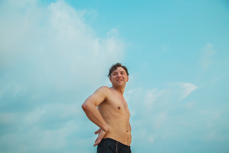 Portrait of a young muscular man against a blue sky.の写真素材