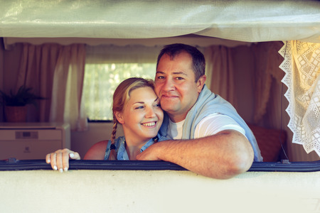 Happy couple of tourists sitting in a camper van on a summer day. Vintage, toned.の写真素材