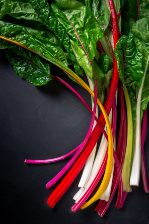 A bunch of beautiful, colorful rainbow chard on a black background, top down viewの写真素材