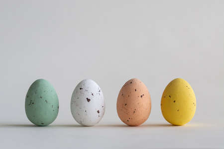 Four beautiful pastel colored chocolate Easter eggs, on white background with copy spaceの写真素材