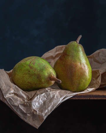 Two beautiful conference pears on a paper bag on black background, copy spaceの写真素材