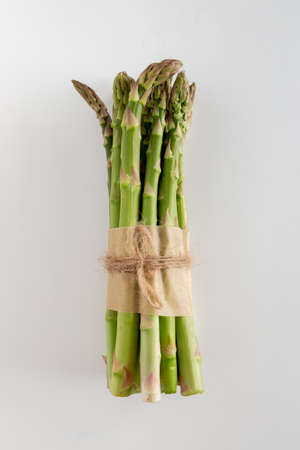 A bundle of beautiful raw green asparagus on a white background, copy space, verticalの写真素材