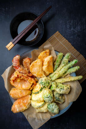 Flatlay of Japanese vegetable tempura with ginger ponzu dipping sauce, black background with copy spaceの写真素材