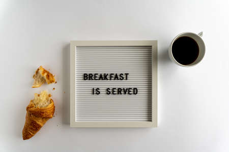 Letterboard With Words That Spell Breakfast Is Served with a croissant and a cup of coffee, on a white background, horizontalの写真素材