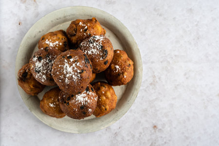 Top down view of a stack of tasty oliebollen (translation: Dutch dough fritters) with a glass of champagne on white background with copyspace on the right, horizontalの写真素材