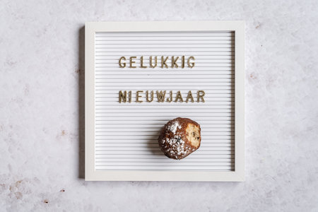 A white letterboard with the text in golden letters spelling Happy New Year (Dutch for Happy New Year) with one oliebolの写真素材