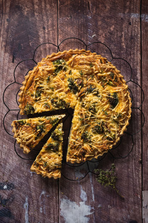 Top down view of a delicious broccoli quiche on wooden table, with two slices cut outの写真素材