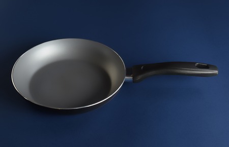 Frying pan on blue background perfect for your delicious recipesの写真素材