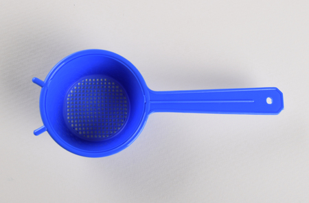 Blue plastic tea strainer isolated on white backgroundの写真素材