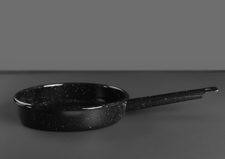 Black enamelled pan with handle on gray background, front viewの写真素材