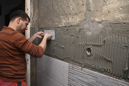 Professional constructor applying glue before laying ceramic tiles on the wall