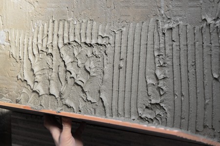 Gluing tiles on the wall. Laying tiles on the wall.  Worker installing big ceramic tiles on the wallsの写真素材