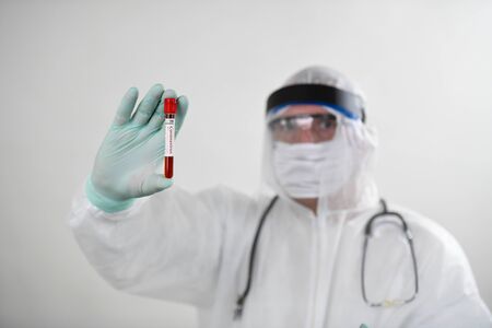 Doctor wearing respiratory mask and holding the Coronavirus Covid-19 blood sample. Doctor working with blood samples in hospital clinic labの写真素材