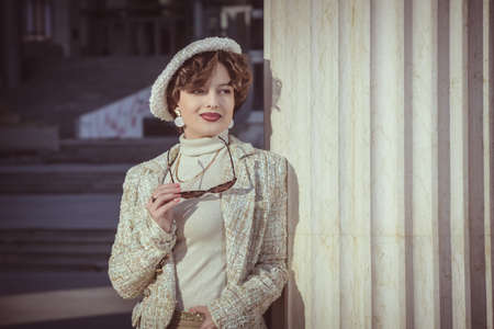 Outdoor fashion portrait of young beautiful fashionable girl with beret, in her hand hold...