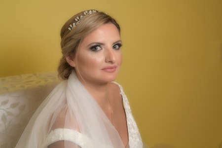 A elegant and beautiful bride at home. Beauty portrait of bride wearing fashion wedding dress with luxury delight make-up and hairstyleの写真素材