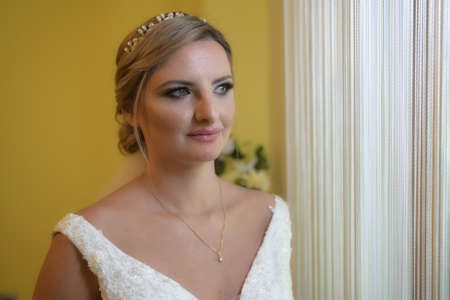 A elegant and beautiful bride at home. Beauty portrait of bride wearing fashion wedding dress with luxury delight make-up and hairstyleの写真素材