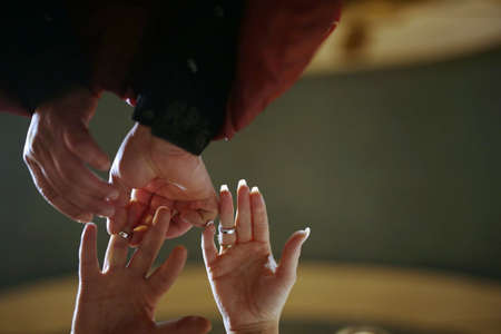 Religious marriage in the Orthodox church. Priest putting on golden wedding ring on bride finger. Wedding matrimony in church. Exchanging wedding rings.の写真素材