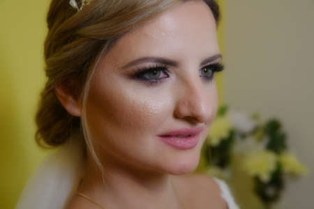 A elegant and beautiful bride at home. Beauty portrait of bride wearing fashion wedding dress with luxury delight make-up and hairstyleの写真素材