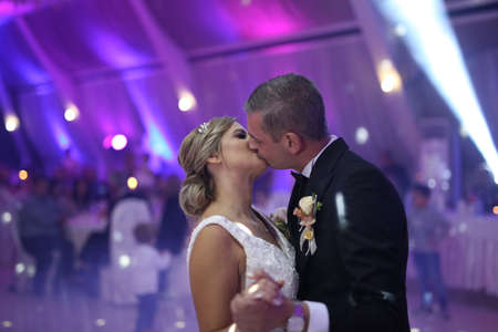 Groom holds bride carefully dancing in the restaurant. First dance bride. Happy bride and groom and their first dance, wedding in the elegant restaurant with a wonderful light and atmosphereの写真素材