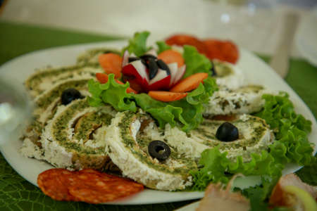 Omelette cheese roll combined with smoked sausage, sliced olives and lettuce salad on a white plate with carrotの写真素材