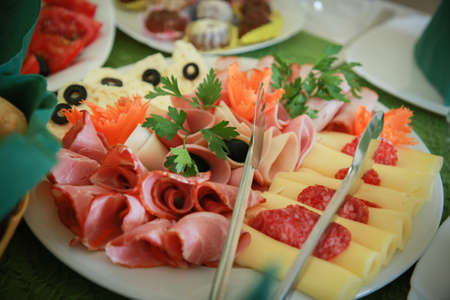 Food tray with delicious salami, pieces of sliced ham, sausage, yellow cheeseの写真素材