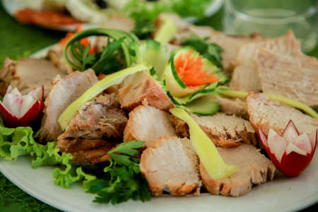 Roast pork loin with cucumber and radish salad. Grilled pork neck served with sliced ??cucumber, grilled pork on a white plateの写真素材