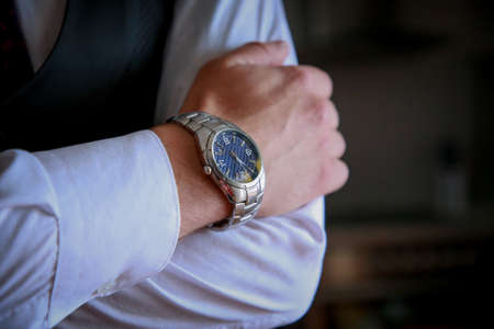 Close up of a man in a white shirt, black suit and a colorful tie. Groom with a watch on his wrist. Photo session of the groom. Wedding pictures. Businessmanの写真素材