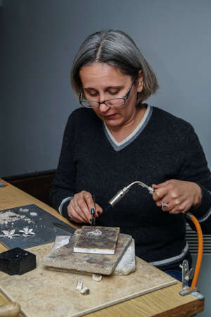 Burner heating in the production and repair of silver jewelry. Heating torch. A female artist makes...