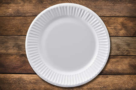 Disposable paper plate on a wooden background. Empty white cardboard plateの写真素材