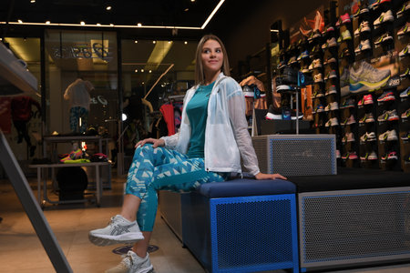 Skopje, Northern Macedonia - March 12, 2021: Asix store in Skopje, Northern Macedonia. Girl photo model dressed in sportswear and sneakers ASICS GEL, sitting and posing in a shop for sports equipmentのeditorial素材