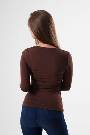 Portrait of woman standing with her back turned, wearing brown blouse and blue jeans, isolated on white backround. Very attractive woman with unusual and long hair. A girl with beautiful hair turned her back to the audience on a white background.の写真素材