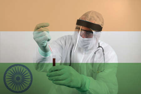 Doctor wearing respiratory mask and holding the Coronavirus Covid-19 blood sample. Scientists test for Covid-19 or Corona virus By using science tubes to research and treat illness in a lab or hospital. Transparent flag of India over the photoの写真素材