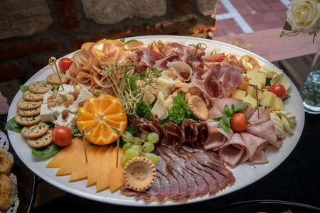 Food tray with delicious and different cheese with delicious salami, pieces of sliced ham, sausageの写真素材