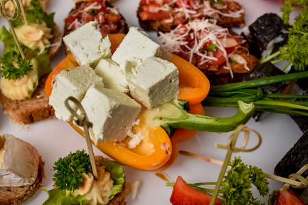 Chopped pieces of feta Greek Turkish cheese placed on pepper and served on the table. Buffet for guests. Food tray with delicious cheeseの写真素材