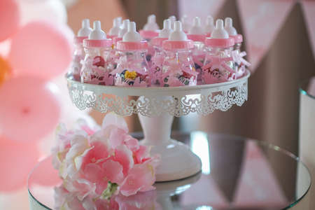 Small baby bottles with nipple with decorations and rose ribbon. Newborn style decorations for birthday partyの写真素材