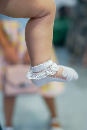 Baby feet dressed in white thin socks close up. Close up of babies feet wearing white cotton socksの写真素材