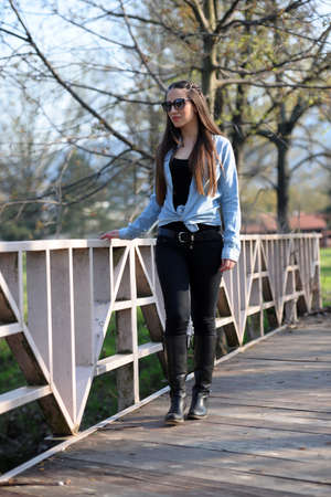 A girl sitting with a blue shirt, leggings and a cap on the head, poses in the city parkの写真素材
