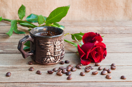 Cup of coffee and red roses on a wooden tableの写真素材